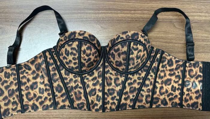 Women's leopard print bustier corset top with padded cups, black boning, and adjustable shoulder straps, displayed flat on a wooden surface. Stylish fitted corset for parties, date nights, and fashion wear in Kenya.
